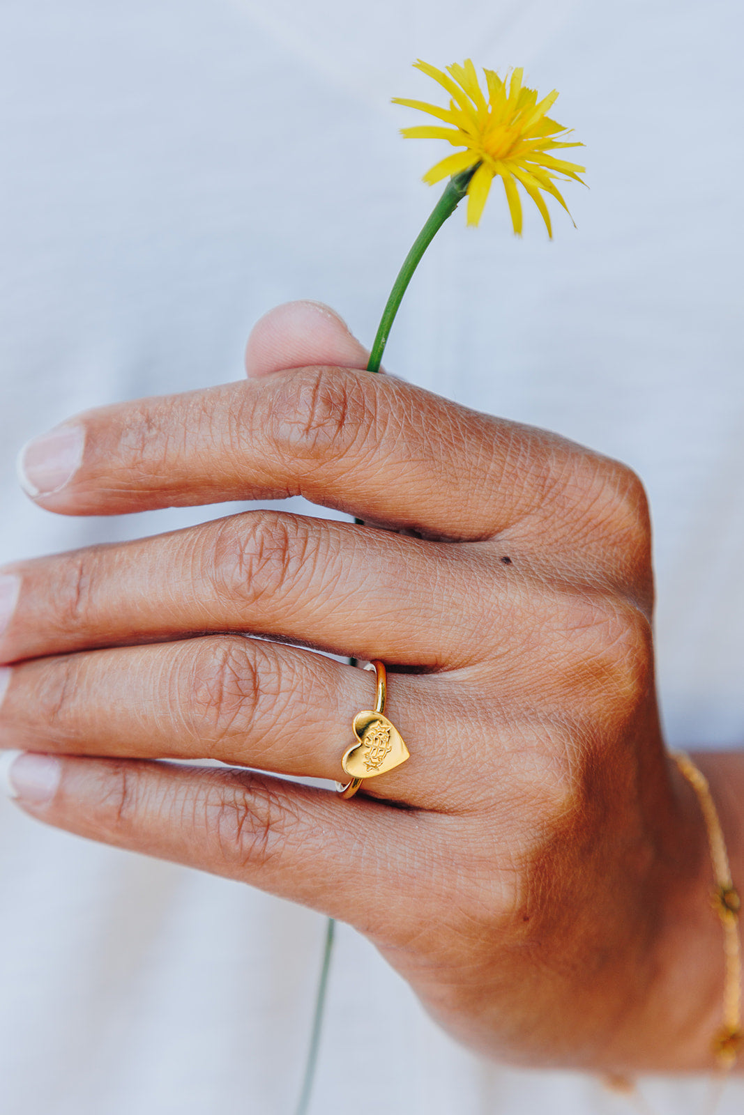 simple gold heart bahai ringstone ring holding yellow dandelion flower