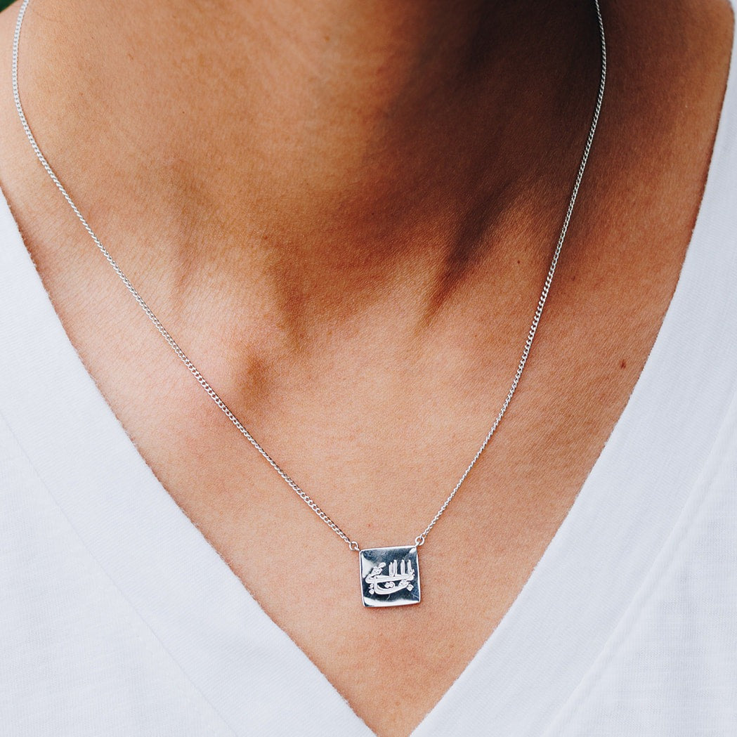 simple silver cushion Baha'i necklace with an engraving of the Greatest Name in Arabic