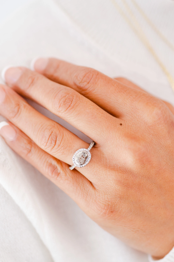 bahai ringstone symbol engraved on a silver horizontal oval signet ring with a halo of micropave round zircon diamonds on a hand model wearing white clothes